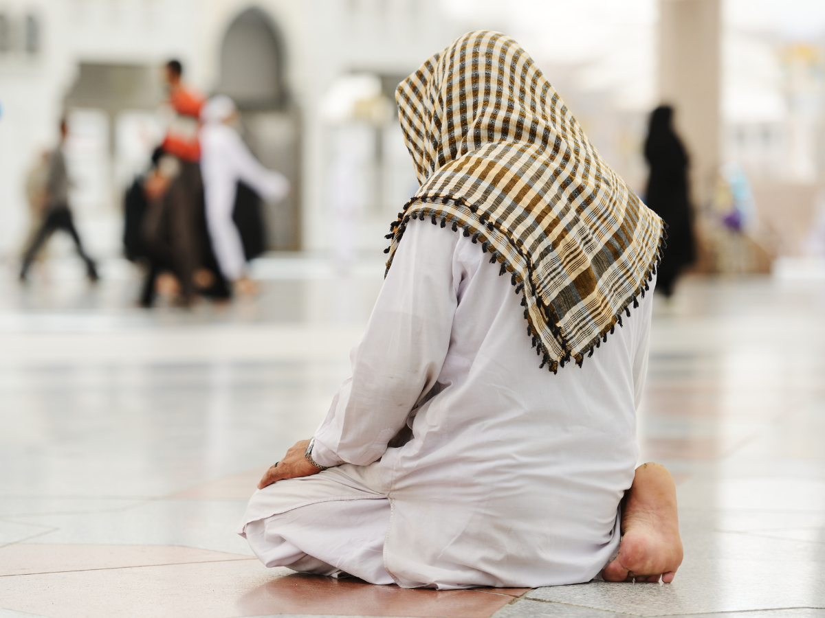 A worshipper in the sitting position whilst praying in the courtyard of a Mosque